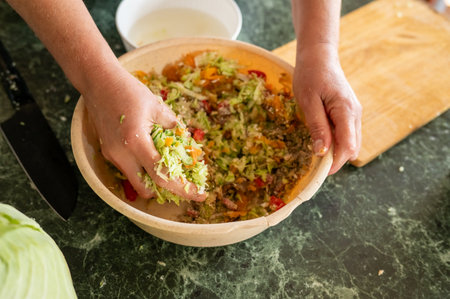 Adult preparing fresh vegetable salad mixing ingredients by hand.の写真素材