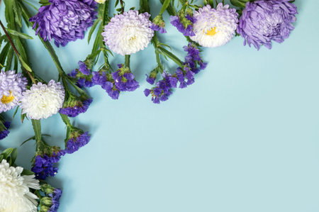 Purple and white flowers on light blue background with greenery.の写真素材