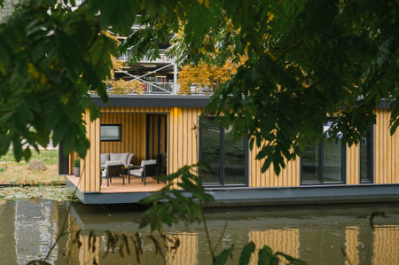 Modern floating home on a tranquil lake surrounded by lush greenery.の写真素材