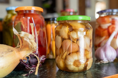 Colorful assortment of pickled vegetables and garlic jars with onions and peppers.の写真素材
