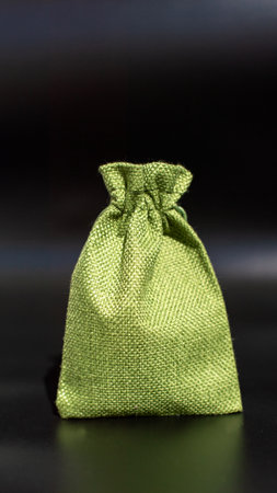 Small green burlap pouch on black background.の写真素材