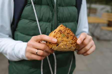 Caucasian young adult holding a nutty pastry outdoors.の写真素材