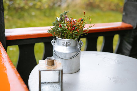 Charming rustic flower arrangement in metal milk can on porch table.の写真素材