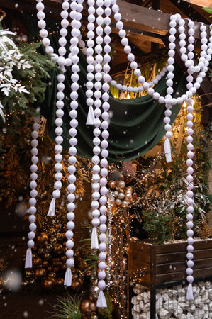 Festive outdoor christmas decor with white baubles and greenery amidst snowfall.の写真素材