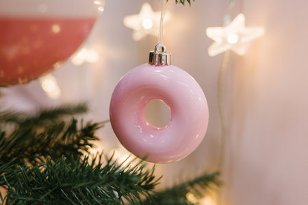 Pink donut ornament hanging on christmas tree with star lights.の写真素材