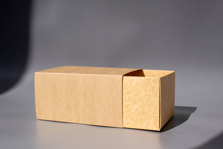 Cardboard box with open sliding drawer on gray background.の写真素材