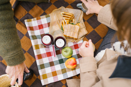 Cozy autumn picnic with sandwiches and candles on checkered blanket.の写真素材