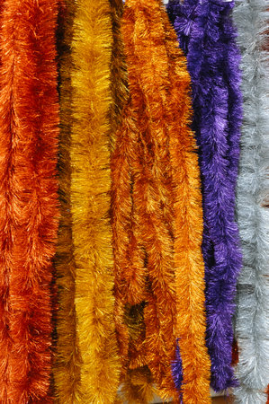 Colorful christmas tinsel garlands in orange, purple, and silver.の写真素材