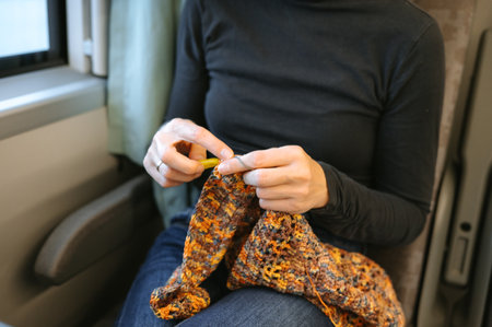 Caucasian female adult knitting on train wearing black sweater and jeans.の写真素材