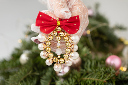 Elegant christmas ornament held by gloved hand against decorated tree background.の写真素材