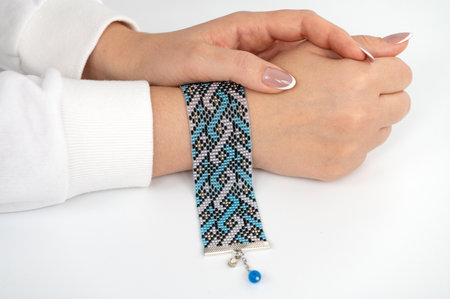 Female hand modeling intricate beaded bracelet with blue and black pattern.の写真素材