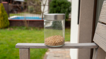 Glass jar of grains on wooden bench outdoors.の写真素材