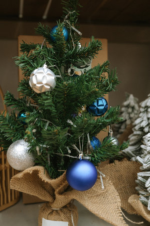 Small decorated christmas tree with blue and silver ornaments in burlap base.の写真素材