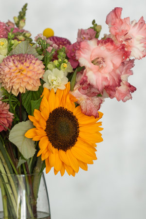 Vibrant floral bouquet with sunflower and gladiolus in a clear vase.の写真素材