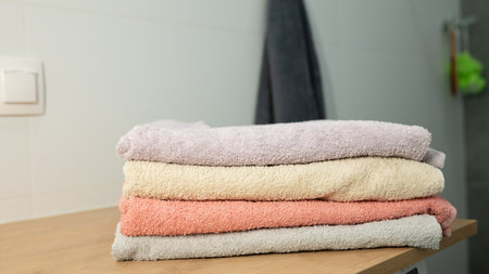 Stacked soft towels in bathroom setting on wooden surface.の写真素材