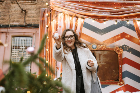 Joyful young caucasian woman playing with snowball at festive winter market.の写真素材