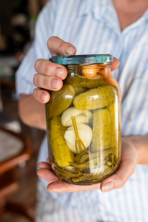 Caucasian male adult holding jar of homemade pickles with onions at home.の写真素材