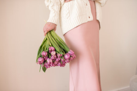 Woman in pink dress holding upside down bouquet of purple tulips. Casual lifestyle and spring concept for greeting card and celebrationの写真素材