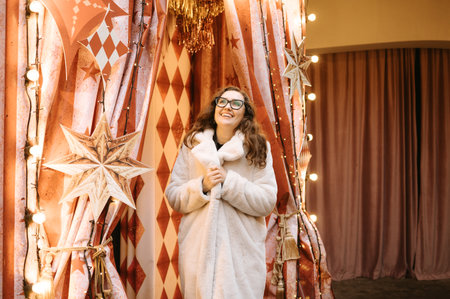 Caucasian female in elegant winter coat enjoys festive Christmas decorations.の写真素材