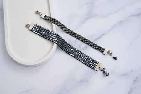 Elegant beaded bracelets on marble surface with charms and clasps.の写真素材