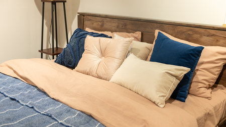 Cozy bedroom with wooden headboard and soft pillows in neutral tones.の写真素材