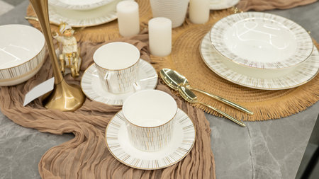 Elegant table setting with gold-rimmed China and decorative figurine.の写真素材