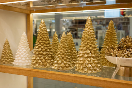 Shimmering gold and white festive candles on wooden shelf display.の写真素材