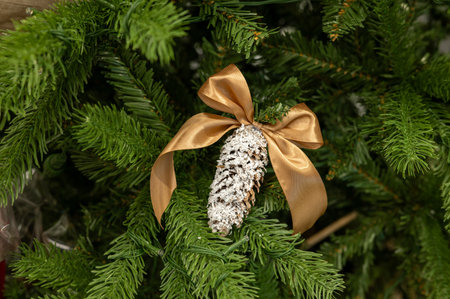 Christmas tree with gold ribbon pinecone ornament and snow accents.の写真素材