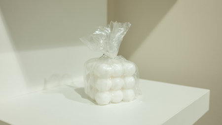Wrapped white cotton balls on minimalist white surface in plastic bag.の写真素材