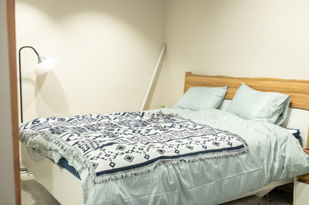 Cozy minimalist bedroom with wooden accents and soft lighting.の写真素材