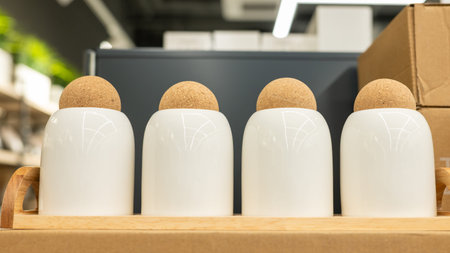 Set of modern white ceramic canisters with cork lids on wooden tray.の写真素材