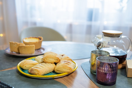 Assorted pastries and tea on table in cozy kitchen setting.の写真素材