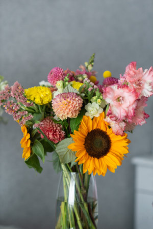 Vibrant mixed flower bouquet in glass vase with sunflower and dahlias.の写真素材