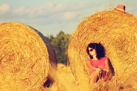 Nice girl sitting near haystack and rest.の写真素材