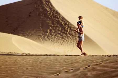 Mom walking with sun in a desert.の写真素材