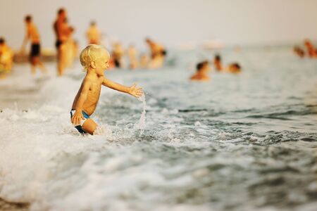 Kid plaing with wave in the seaの写真素材