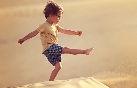 Handsome baby boy walking and playing alone in the desert in Maspalomas, Gran Canaria.の写真素材