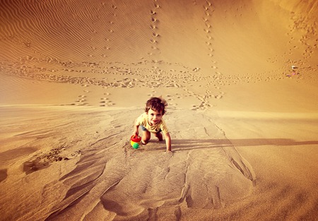 Handsome baby boy walking and playing alone in the desert in Maspalomas, Gran Canaria.の写真素材