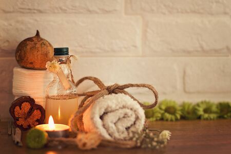 Spa setting with towels, oil, flowers and wooden heart on white bricks background with space for your textの写真素材