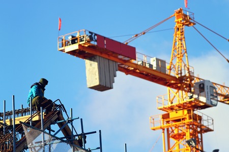 Worker man sitting in the pile and looking at the crane. New building of skyscraper.