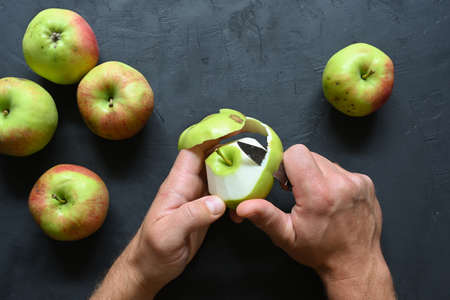 Piece of cut and peeled apple, peels and seeds, on black background