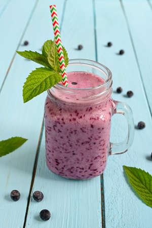 Blueberry smoothie with mint in mason jar with straw against a wood backgroundの写真素材