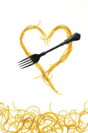 Swirls of cooked spaghetti with fork. Spaghetti heart shape