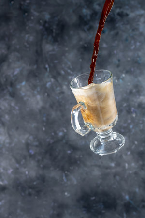 coffee with milk and cookies in the shape of hearts. the process of pouring coffee into a glass of milk. levitationの写真素材