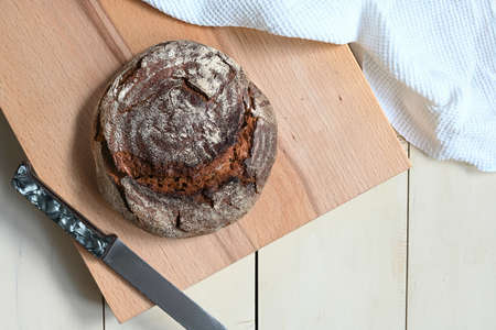 traditional round artisan rye bread on wooden cutting board. light background.