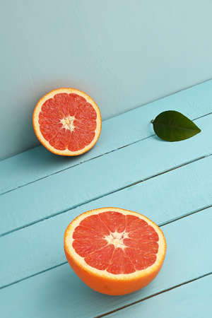 Red grapefruit cut in half on a blue wooden rustic background.の写真素材