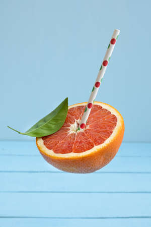 part of red grapefruit with straw on blue backgroundの写真素材