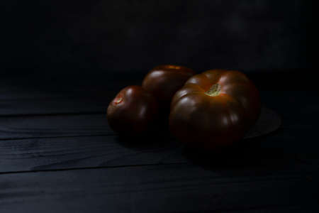 Black tasty juicy kumato tomatoes on black backgroundの写真素材
