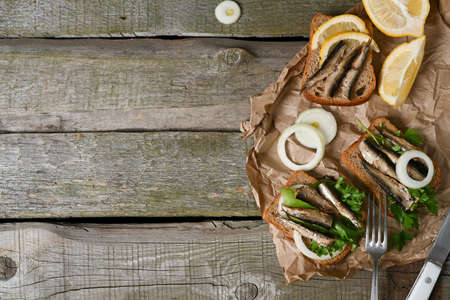 Sandwich with smoked sprats in oil on wooden table. top view.の写真素材