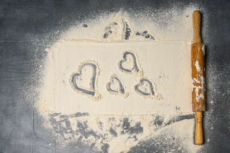 Rolling pin and white flour on a dark surface. Top view